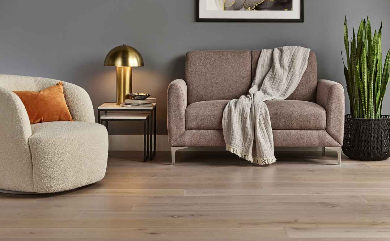 Hardwood flooring in a living room with a brown loveseat and cream accent chair